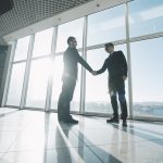 Two business men in an office building shaking hands